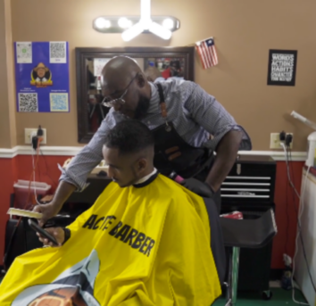 Barber is showing client how to view Saving Lungs Behind the Chair resources.