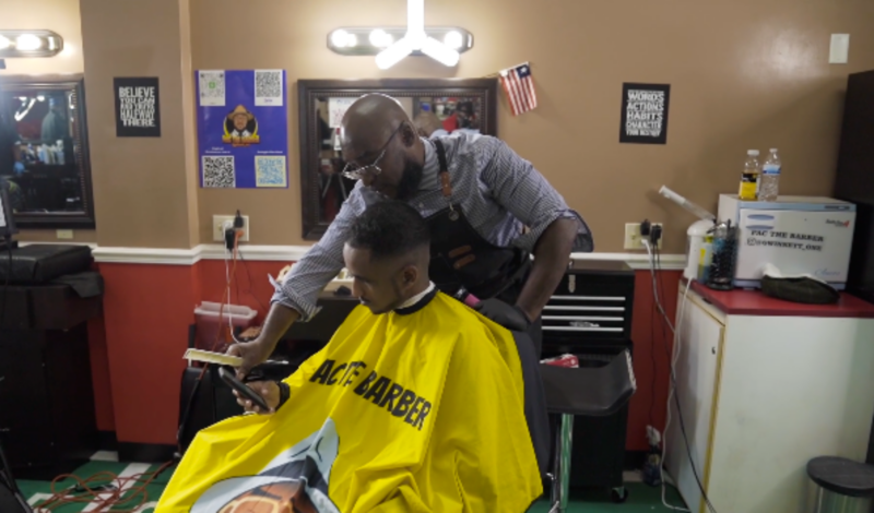 Barber is showing client how to view Saving Lungs Behind the Chair resources.