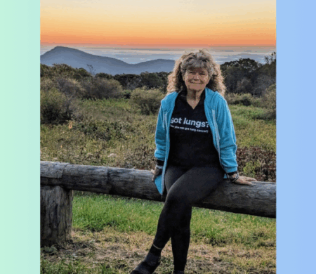 Donnita Butler sitting on a log railing with a beautiful sunset behind her.