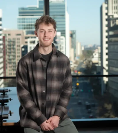 Zach Shefska sitting in an office with a cityscape background